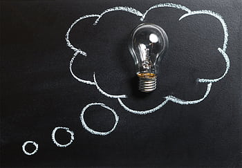 Light bulb laying on chalkboard with drawn thought bubble, symbolizing creative ideas. HD wallpaper