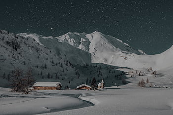 A serene winter night scene featuring a snow-covered mountain resort under a starry sky, ideal for travel and nature enthusiasts. HD wallpaper