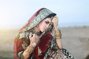Elegant Indian woman in traditional attire posing outdoors, showcasing exquisite jewelry and fabrics. HD wallpaper