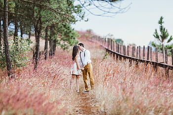 A romantic couple shares a kiss in a beautiful countryside setting, surrounded by fall colors. HD wallpaper