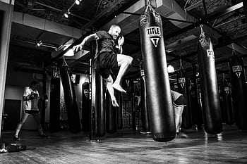 Action-packed scene of a man training in a gym with punching bags. HD wallpaper
