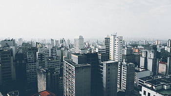 Aerial view of a dense urban cityscape with numerous skyscrapers and high-rise buildings under a cloudy sky. HD wallpaper