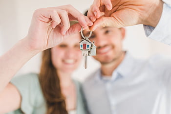 Young couple holding keys to their new home, symbolizing a fresh start and investment in real estate. HD wallpaper