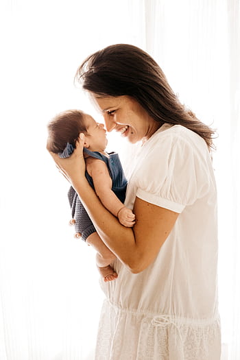 A joyful mother cradles her infant closely, expressing love and happiness. HD phone wallpaper