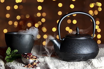A serene still life of a black teapot and teacup with herbal tea, exuding warmth and tradition. HD wallpaper