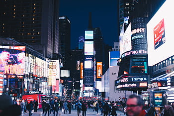 Bustling night scene in Times Square, New York City, illuminated with vibrant advertisements. HD wallpaper
