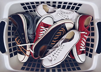 A variety of vintage sneakers piled in a white laundry basket. Perfect mix of style and nostalgia. HD wallpaper