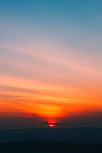 Dramatic sunrise with vibrant orange and blue hues painting the sky, creating a serene and peaceful scene. HD phone wallpaper