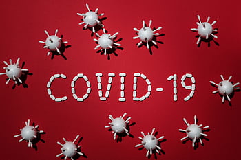 Creative depiction of COVID-19 using pills and virus models on a red backdrop. HD wallpaper