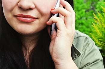 Close-up of a woman chatting on her smart outside with greenery in the background. HD wallpaper