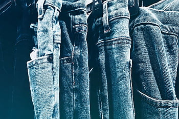 A collection of blue denim jeans hanging closely on a rack in a retail store. HD wallpaper