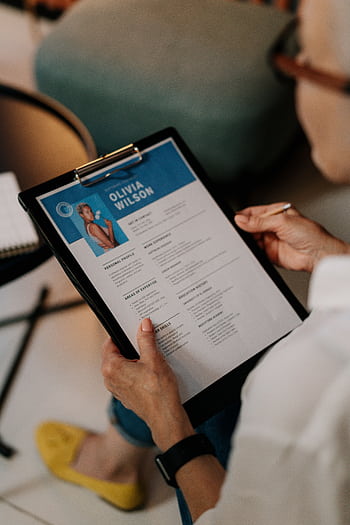 An HR professional reviews a resume on a clipboard during an office meeting. HD phone wallpaper