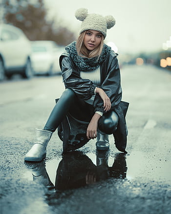 Stylish woman in winter streetwear posing outdoors on a wet street. HD phone wallpaper