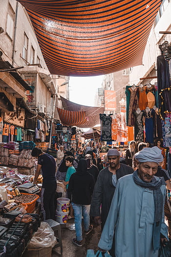 Vibrant marketplace in Cairo with people shopping under striped canopies. HD phone wallpaper
