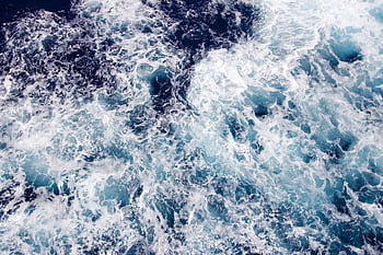 A dramatic view of swirling ocean waves captured from above, showcasing the beauty of maritime motion. HD wallpaper