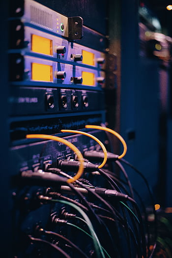 Close-up of network cables and ports in a server rack, showcasing connectivity. HD phone wallpaper