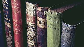 Close-up of vintage books with ornate covers, evoking knowledge and history. HD wallpaper