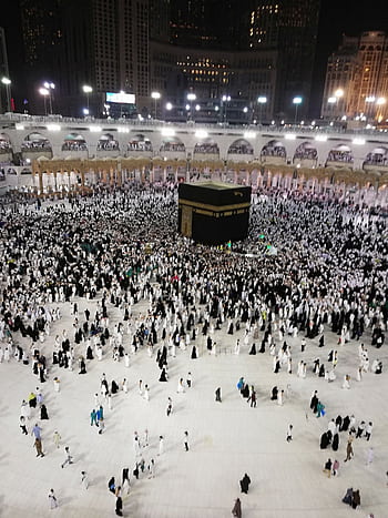 Night view of the Kaaba at Al Masjid Al Haram with pilgrims gathered for worship in Mecca. HD phone wallpaper
