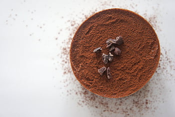 Top view of a rich chocolate dessert dusted with cocoa powder on a white background. HD wallpaper