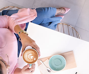 Stylish woman enjoying a cappuccino with latte art at a chic Dubai cafe. HD wallpaper