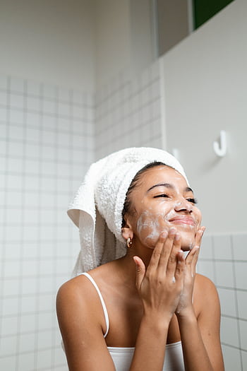 A young woman enjoying her skincare routine with a towel wrapped, indoors. HD phone wallpaper