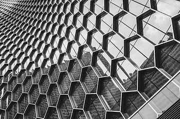 Black and white of a modern building facade with a geometric hexagonal pattern. HD wallpaper