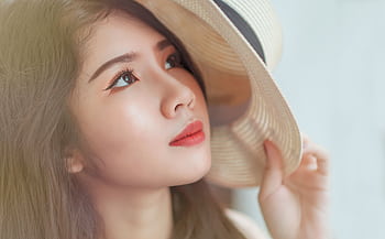 Close-up of a young woman with eye makeup holding a stylish hat. HD wallpaper