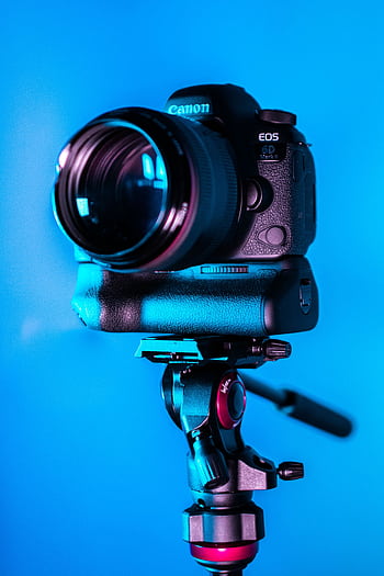 Close-up of a DSLR camera on a tripod with a blue background. HD phone wallpaper
