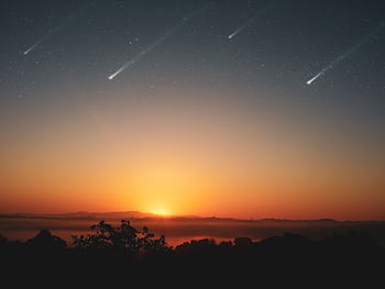 Experience the awe-inspiring beauty of a sunrise with shooting stars across a clear sky, perfect for serene landscapes. HD wallpaper