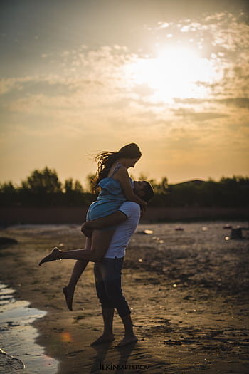 A loving couple embraces during a romantic sunset on a beach in Baku, Azerbaijan. HD phone wallpaper