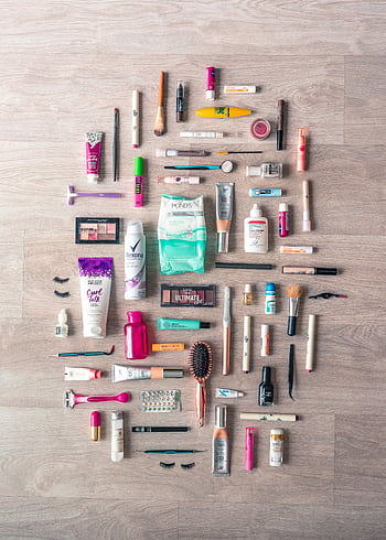 A diverse collection of beauty and grooming products neatly arranged on a wooden surface in a flatlay style. HD phone wallpaper
