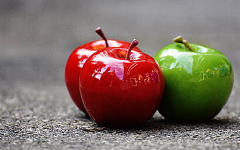 Close-up of shiny red and green apples on a textured surface, showcasing freshness and vibrant colors. HD wallpaper