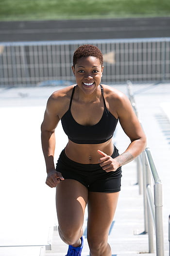 Fit woman with short hair jogging outdoors, showing strength and happiness. HD phone wallpaper
