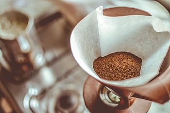 A close-up of ground coffee in a pour-over filter on a stovetop background, ideal for coffee enthusiasts. HD wallpaper