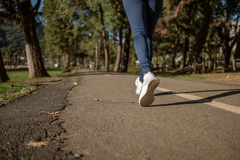 A woman jogging on a path through a park, showcasing fitness and healthy lifestyle outdoors. HD wallpaper