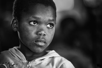 A black and white portrait of a child with a thoughtful expression. HD wallpaper