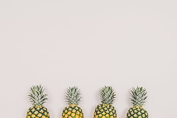 A minimalist of four pineapples aligned on a white background, perfect for tropical themes. HD wallpaper