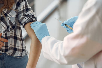 A medical professional giving a vaccination to a patient indoors, emphasizing healthcare. HD wallpaper
