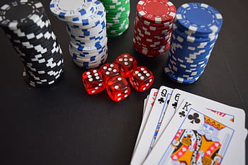 A vibrant display of casino chips, dice, and playing cards set on a table, embodying chance and excitement. HD wallpaper