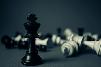 Black king chess piece stands tall among fallen pieces, symbolizing strategy and triumph. HD wallpaper