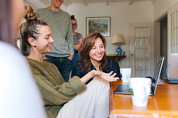 A group of friends enjoying casual leisure time indoors with smiles and relaxed atmosphere. HD wallpaper