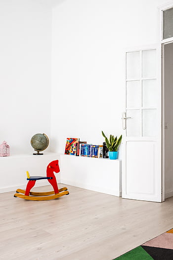 Bright minimalist kids room featuring a red wooden rocking horse, plants, and globe. HD phone wallpaper