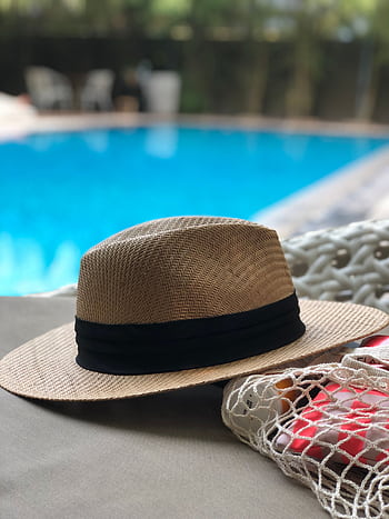 A stylish straw hat rests poolside, capturing a serene summer vibe. HD phone wallpaper
