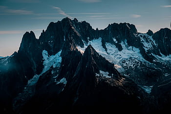 Majestic mountain peaks covered in snow and ice under a clear sky, ideal for nature graphy. HD wallpaper