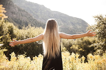 Young woman with arms open, enjoying dom in a mountainous landscape. HD wallpaper