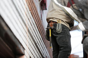 Close-up of a construction worker with hammer and tools, focused on the job. HD wallpaper