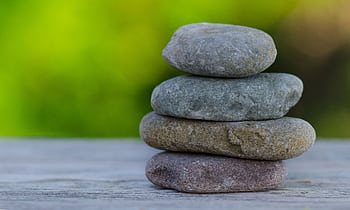 Four smooth stones stacked outdoors, symbolizing balance and tranquility. HD wallpaper