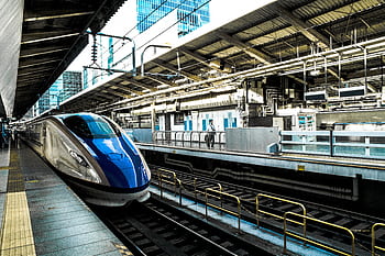 Sleek bullet train at a busy city station, epitomizing speed and modern transportation. HD wallpaper