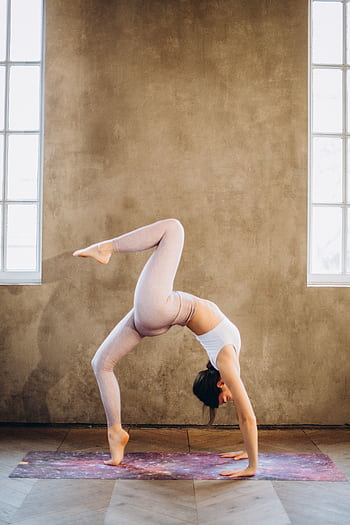 Woman performing a graceful wheel pose balancing on one leg in a bright yoga studio. HD phone wallpaper