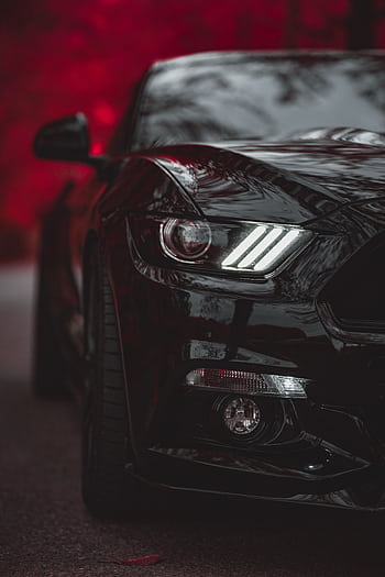 Close-up of a black luxury car with striking headlights against a red blurred background. HD phone wallpaper